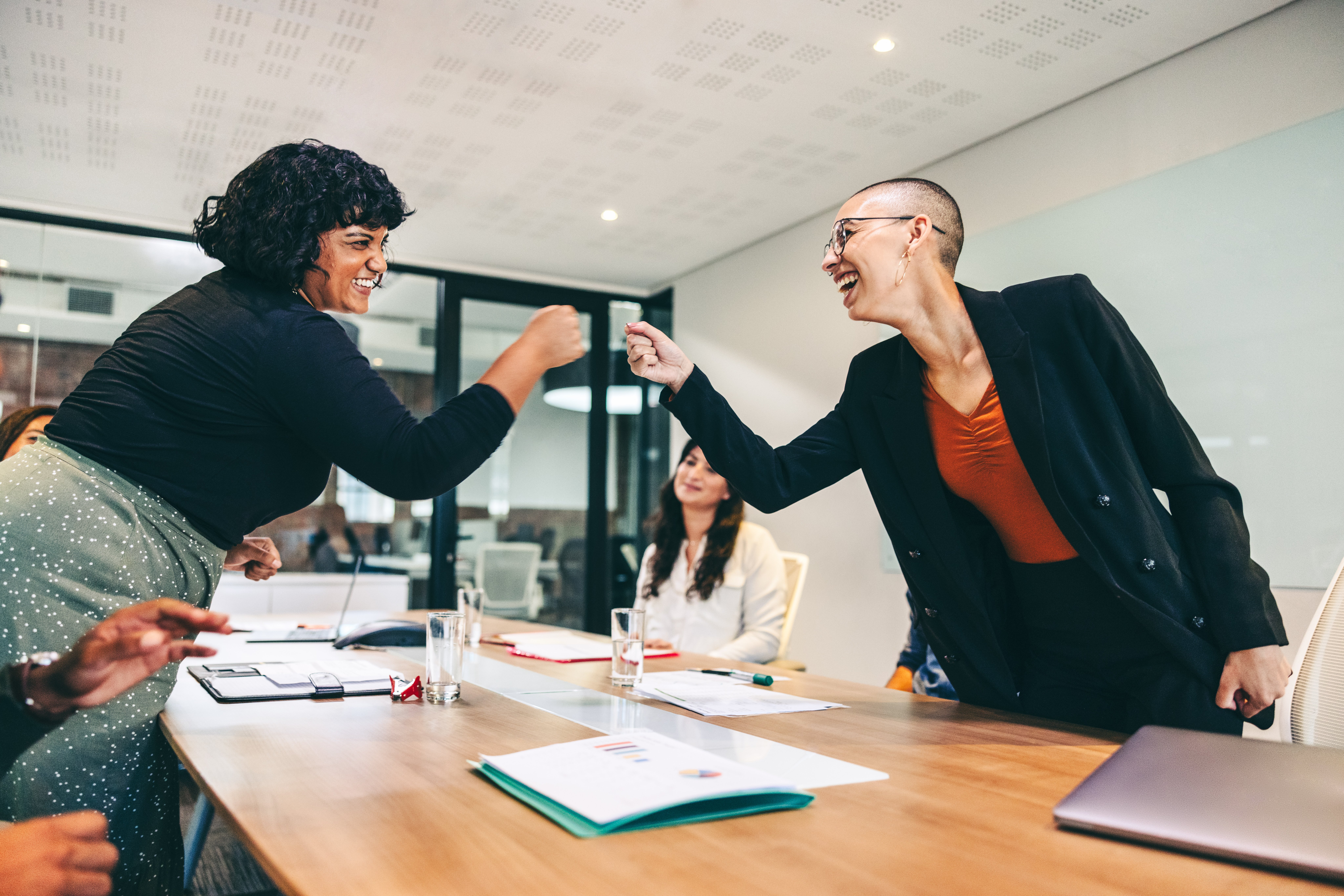STOCK Cheery businesswomen fist bumping each other before a meeting.jpg
